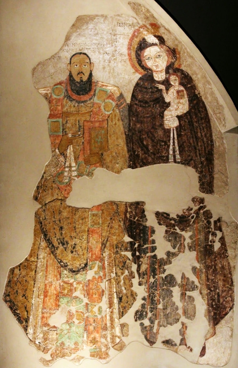 A medieval wall painting of a dark-skinned bearded bishop in rich vestments holding a book, standing beside the Virgin Mary holding the Christ child