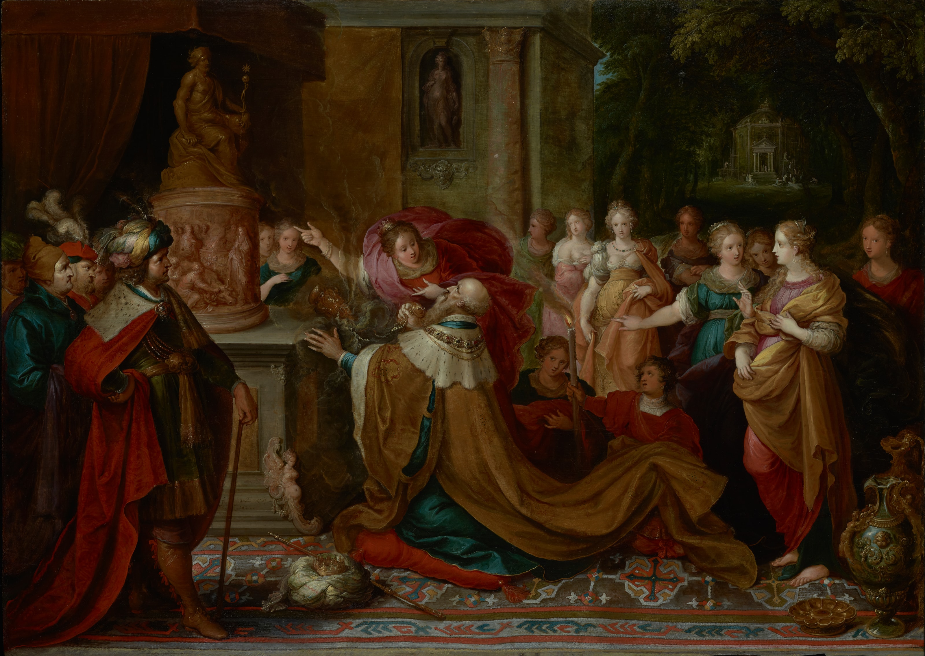 King Solomon kneels in a gold robe before a pagan statue while a crowd of his foreign wives gathers around him and one points him toward the idol