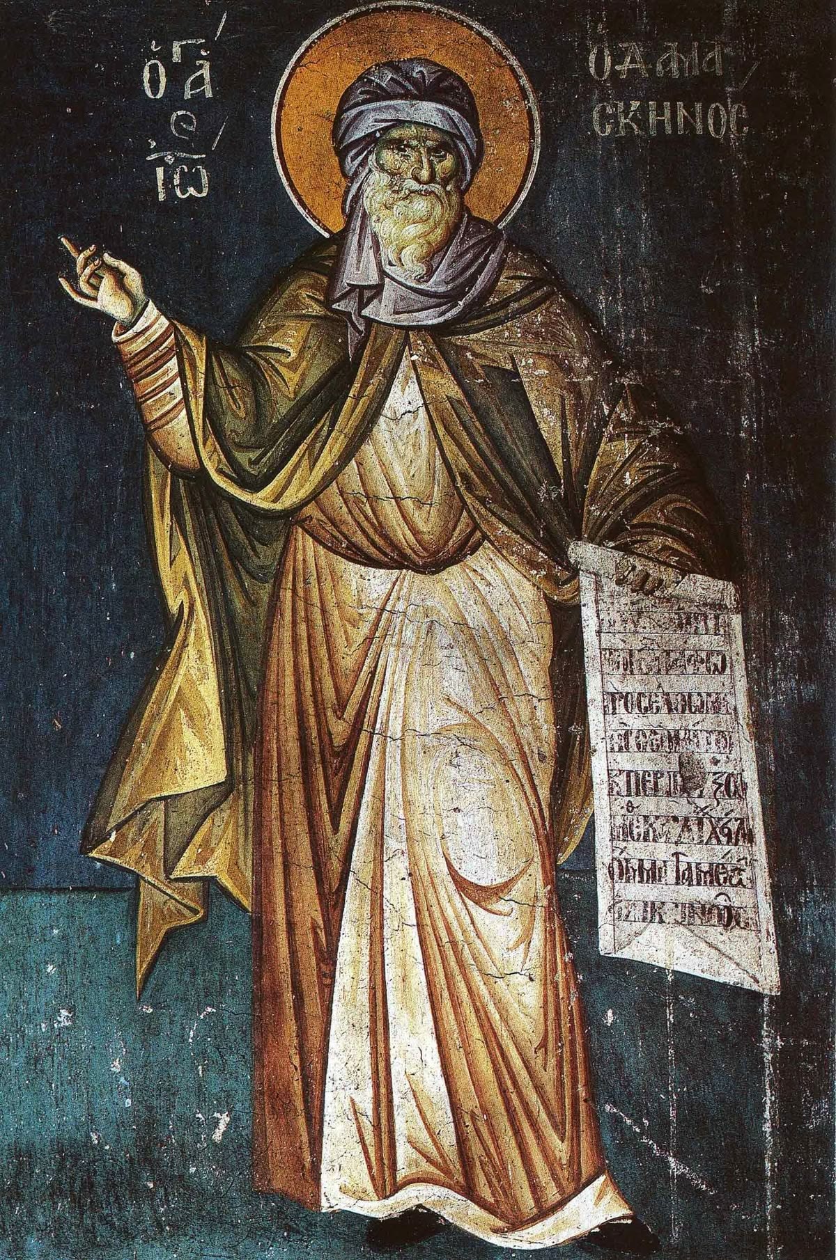 Fresco of John of Damascus standing in a monk's robe and turban, his right hand raised and a written scroll in his left